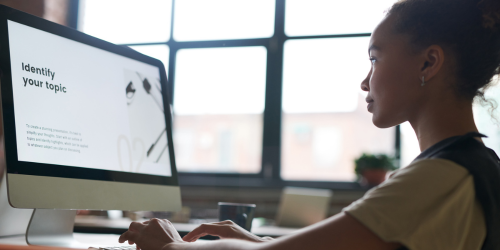 Young woman looking at computer screen with an AI prompt