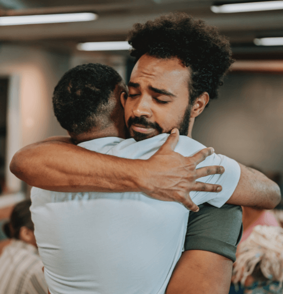 Man in recovery hugging sponsor at a nonprofit