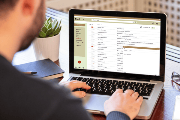 Image of a man looking at emails on a laptop