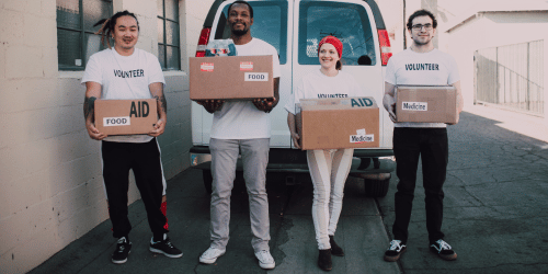 Image of a group of volunteers holding boxes with medical aid, food, and more
