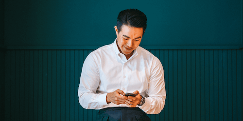 Image of man in a white shirt looking at a phone